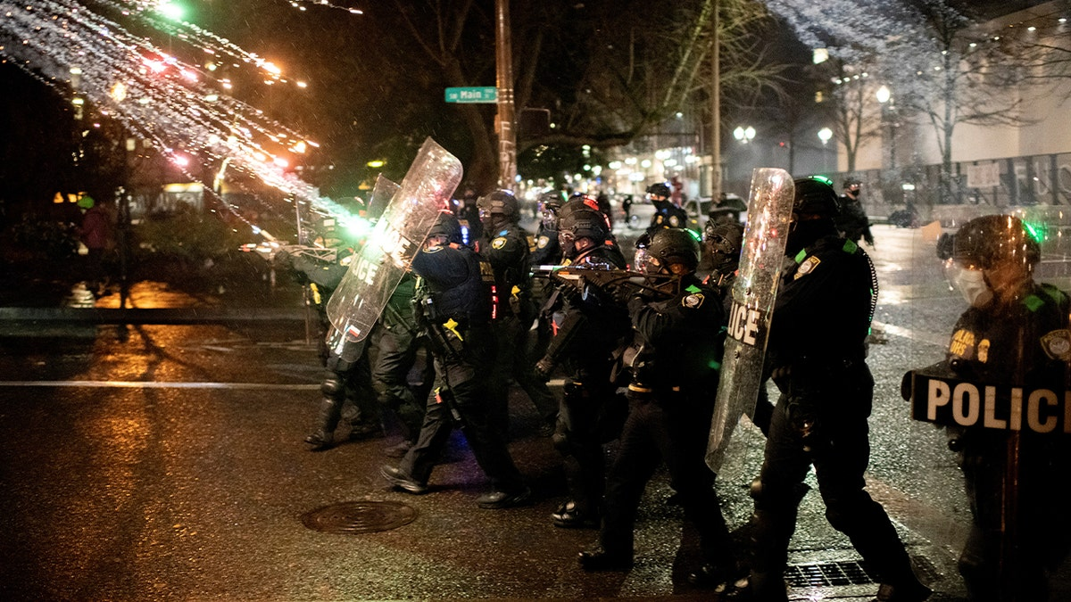 a projectile firework hits a line of cops in riot gear