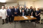 a group of mostly men politicians with a couple of women and a doctor all eerily smiling while the governor signs laws into effect