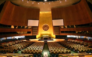 the un general assembly chambers with golden, warm light and all empty chairs