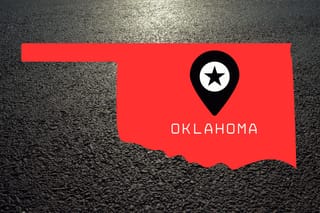 A red rendering of the outline of Oklahoma over asphalt