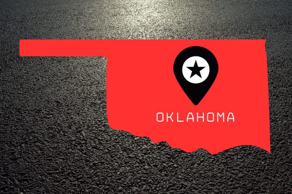 A red rendering of the outline of Oklahoma over asphalt